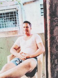 Young man sitting in front of building