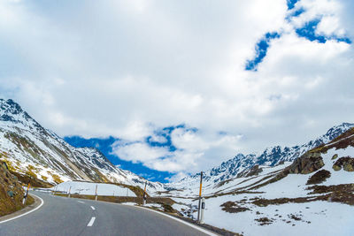 Snow covered road by mountain against sky