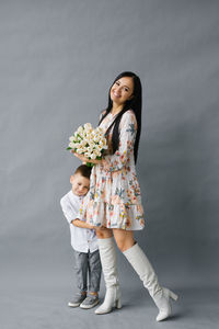 Photo portrait of a brunette girl holding a bouquet of white tulips in her hands, standing next 