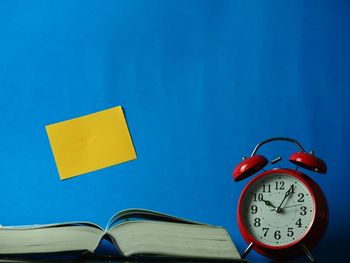 Close-up of clock on table against blue background