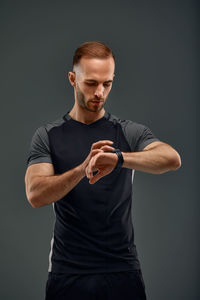 Portrait of young man exercising against gray background