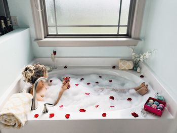 High angle view of woman with fruits in glass bathing in tub