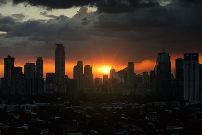 Modern buildings in city against sky during sunset