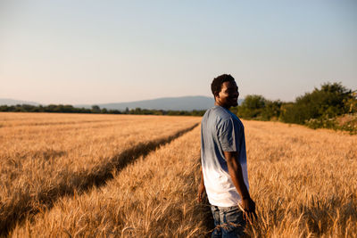 Smiling young man standing on crop field