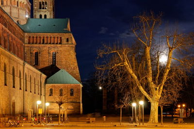 Illuminated building by street against sky at night