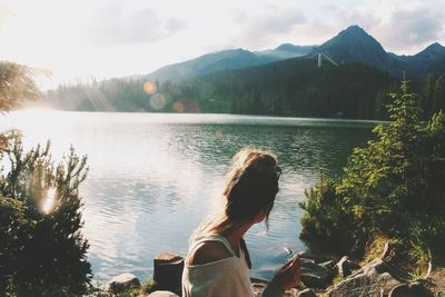 Woman looking at lake while resting on sunny day