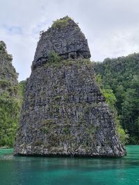 View of rock formation in sea against sky