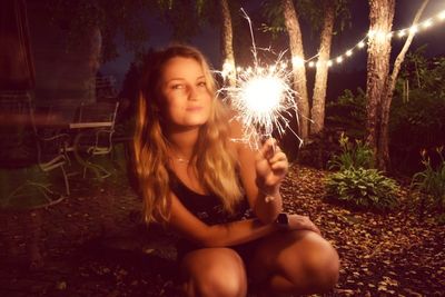 Portrait of beautiful woman sitting in park at night