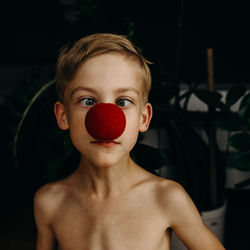Close-up portrait of boy wearing red nose