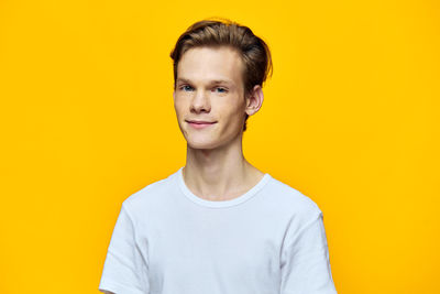 Portrait of young woman standing against yellow background