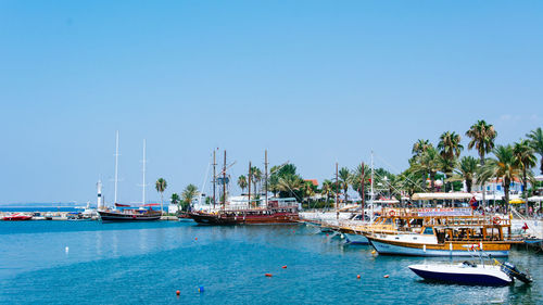 Sailboats moored at harbor against clear blue sky