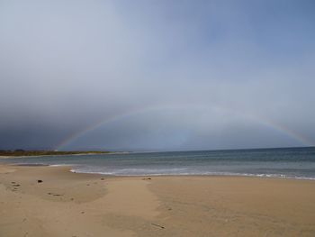 Scenic view of sea against rainbow in sky