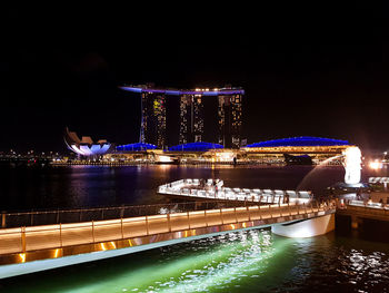 Illuminated bridge over river against sky at night