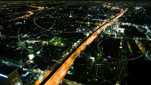 High angle view of illuminated street amidst buildings in city at night