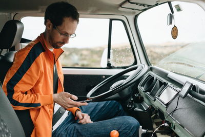 Mid adult man using mobile while sitting in car