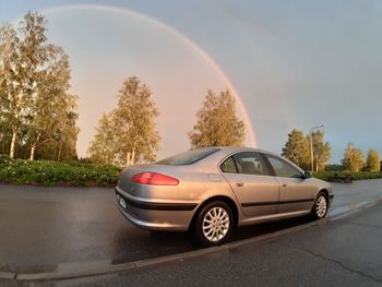 Cars on road against rainbow in city