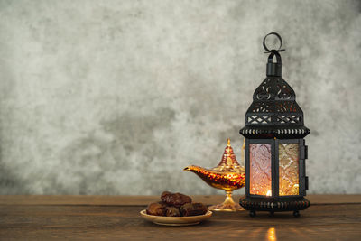 Close-up of illuminated lantern on table against wall