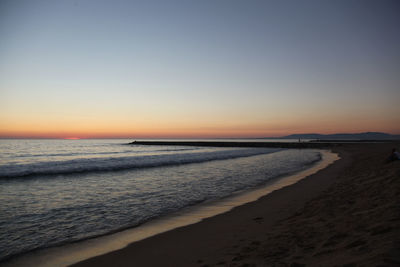 Scenic view of beach against clear sky during sunset