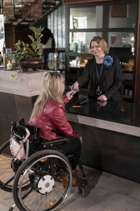 Woman on wheelchair talking to receptionist