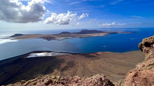 Scenic view of graciosa island from cliff of lanzarote island with deep blue sea against sky