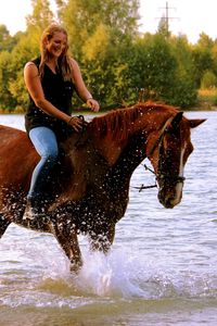 Young woman riding horse in water