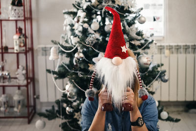 Woman hiding behind christmas toy at home