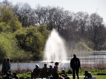 People enjoying at fountain against trees
