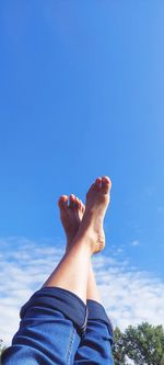 Low section of person legs against blue sky
