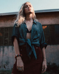 Young woman looking away while standing against wall