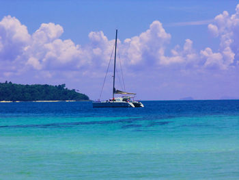 Boat sailing in sea against cloudy sky