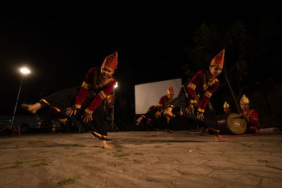 Low angle view of traditional dance group dancing on street at night