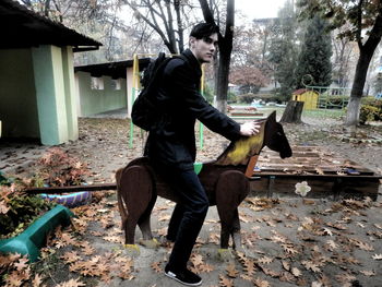 Man sitting on horse statue during autumn