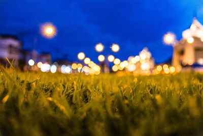 Defocused image of illuminated field against sky at night