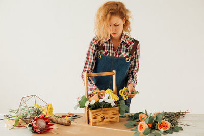 Woman standing by plant against white background