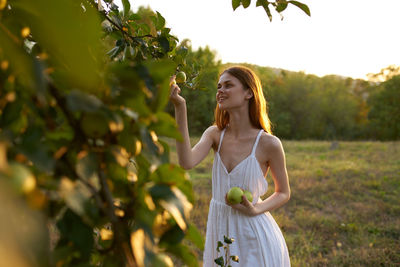 Full length of woman standing by tree