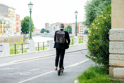 Young businessman in a suit riding an electric scooter while commuting to work in city.