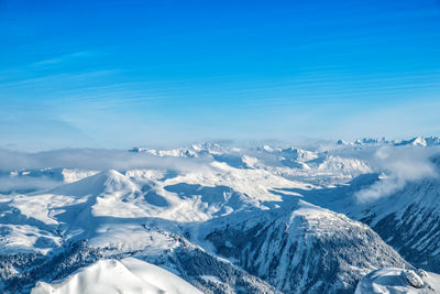 Scenic view of snowcapped mountains against blue sky