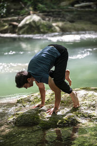 Side view of man sitting on rock