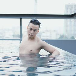 Portrait of shirtless man swimming in pool
