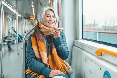 Portrait of young woman standing in train