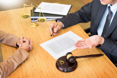 Midsection of lawyer sitting with client at office