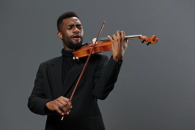 Man playing violin against black background