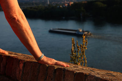 Cropped hands on retaining wall by river