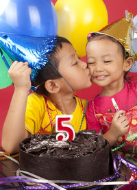 Close-up of boy kissing sister while standing by birthday cake in party