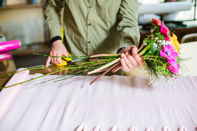 Midsection of florist holding making bouquet at table in flower shop