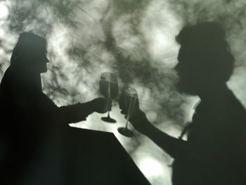 Low angle view of silhouette people having drink against cloudy sky