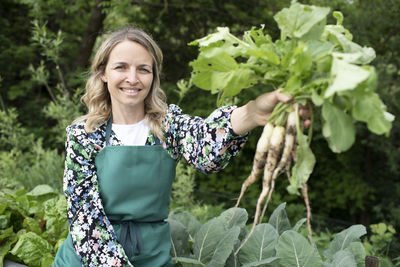 Portrait of smiling young woman holding leaf