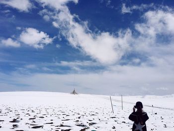 Woman standing on snow covered land against sky