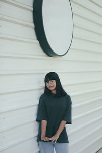 Portrait of girl standing against wall