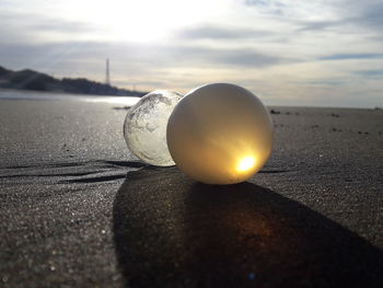 Close-up of ball on beach against sky during sunset